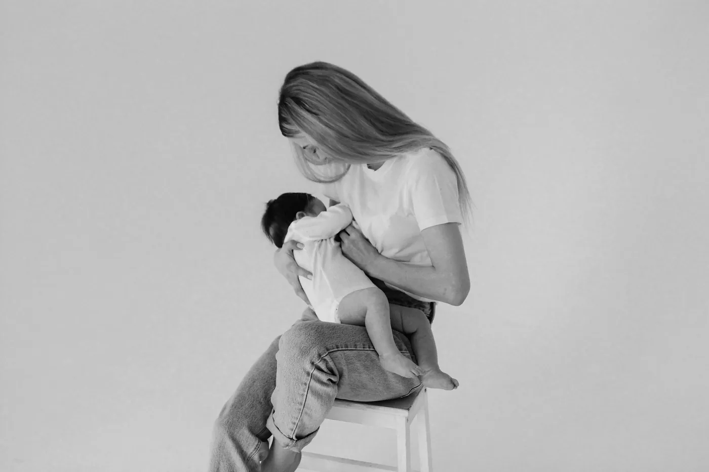 Photo en noir et blanc : une mère assise tient son enfant contre elle.