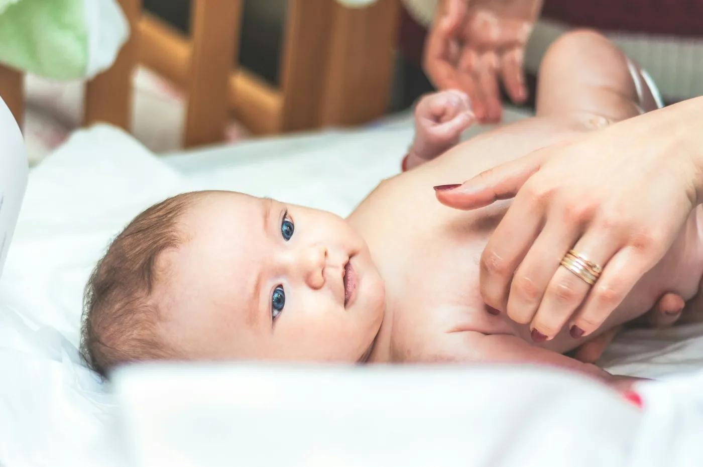 Des mains massent doucement le ventre d'un bébé allongé.